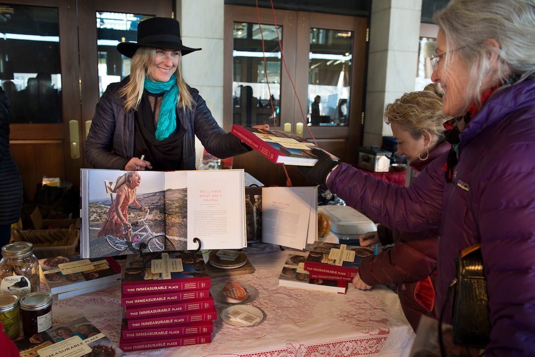 (Scott Sommerdorf   |  The Salt Lake Tribune)   Jen Castle, co-owner of Hell's Backbone Grill in Boulder, hands a copy of the new cookbook, "This Immeasurable Place: Food and Farming from the Edge of Wilderness," to Margie Batson at the Winter Market at the Rio Grande Depot, Saturday, December 9, 2017.  
