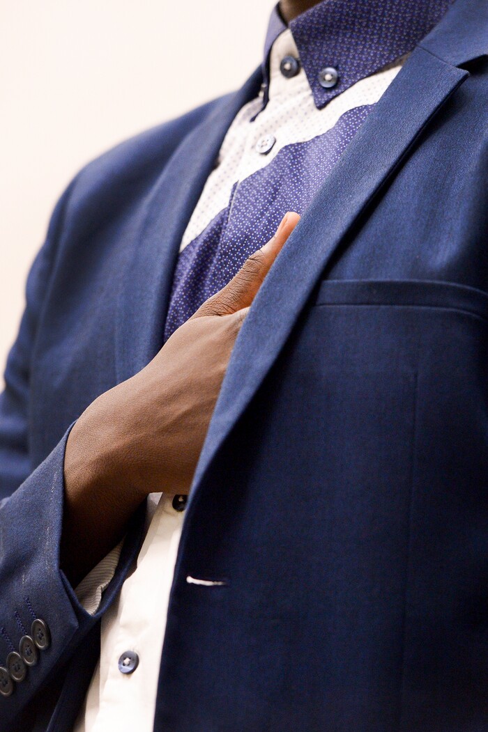 Leah Hogsten | The Salt Lake Tribune Andrew Charles of Uganda slips his hand inside his sport coat during the singing of the National Anthem at his youth naturalization ceremony at the Viridian Event Center in West Jordan, Monday, August 6, 2018. With hands on their heart 21 participants, ages 5 to 22, representing 8 countries, spoke the oath of citizenship as America's newest citizens.