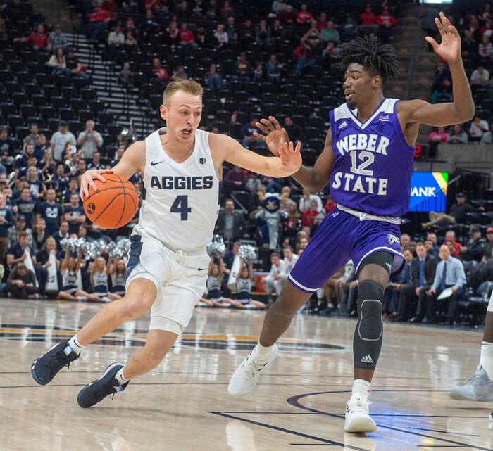 (Rick Egan  |  The Salt Lake Tribune)      Utah State Aggies guard Crew Ainge (4) takes the ball down the middle, as Weber State Wildcats guard Israel Barnes (12) defends, in basketball acton in the Beehive Classic, between against the Utah State Aggies and Weber State Wildcats, a the Vivint Smart Home Arena, Saturday December 8, 2018.

 