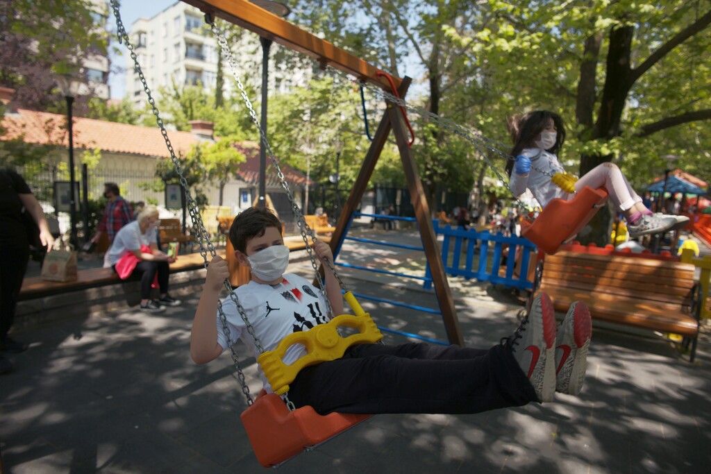 (Burhan Ozbilici | AP file photo)  Children wearing face masks for protection against the coronavirus, play on swings in Kugulu public garden, in Ankara, Turkey, Wednesday, May 13, 2020.