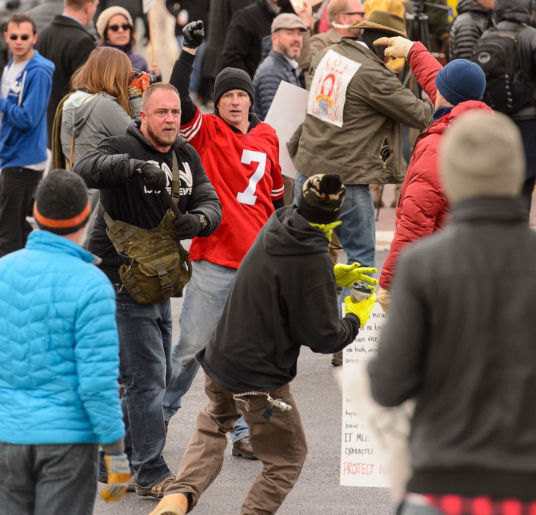 (Trent Nelson | The Salt Lake Tribune)  A man pulls out a self defense baton as another man prepares to throw a drink at him. Protesters rally against a visit by President Donald Trump, Monday December 4, 2017.