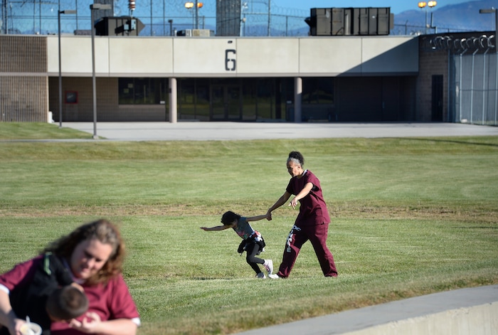 (Scott Sommerdorf   |  The Salt Lake Tribune)   Inmate Angela Rekoutis is pulled along by her energetic daughter Ava as they play in the prison yard during "Kids Day" at the Utah State Prison, Saturday, October 7, 2017. There were also games and snacks set up in the gymnasium.