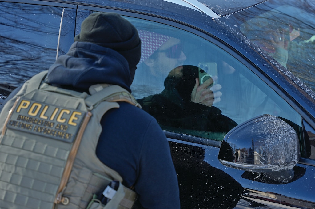 A person points their phone camera at a federal immigration officer as their vehicle is stopped Friday, Jan. 23, 2026, in Minneapolis. (AP Photo/Angelina Katsanis)