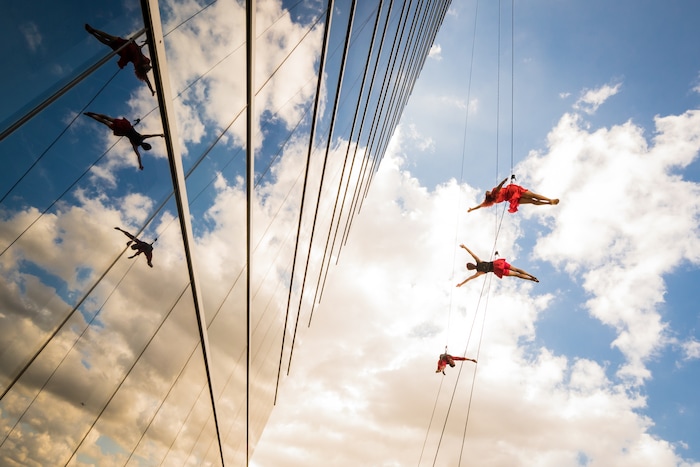 (Photo courtesy of James Adamson) Oakland, Calif.-based “vertical dance” company BANDALOOP performs in Dallas. They will be appearing at the Utah Arts Festival June 21-24, and will perform twice daily (5:30 and 7 p.m.) on the six-story library glass wall above the reflecting pool.