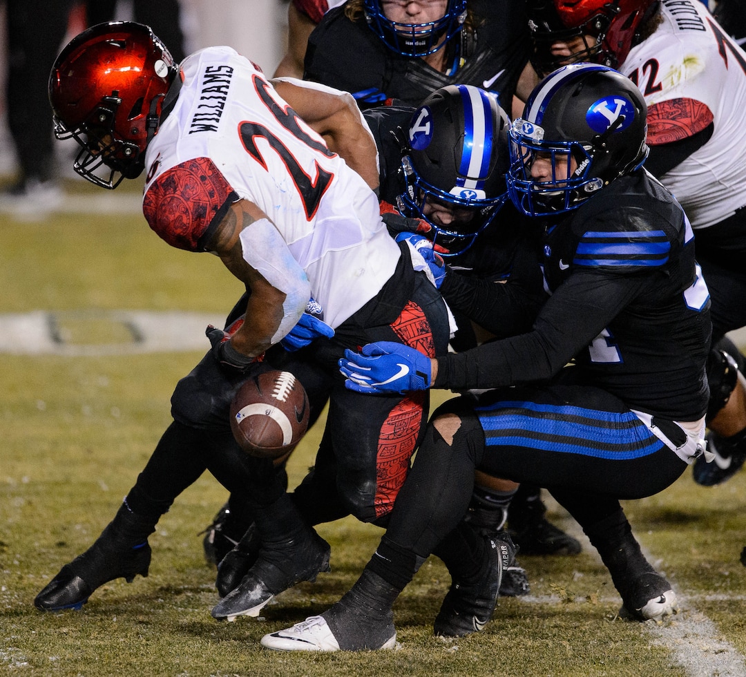 (Trent Nelson  |  The Salt Lake Tribune) San Diego State Aztecs running back Kaegun Williams (26) is stripped of the ball by Brigham Young Cougars linebacker Kavika Fonua (34) as BYU hosts San Diego State, NCAA football in Provo on Saturday, December 12, 2020.