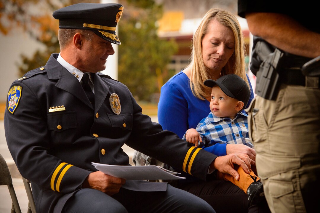 (Trent Nelson  |  The Salt Lake Tribune) South Salt Lake Police Deputy Chief Dwayne Ruth reaches out to Jackson Romrell at the dedication ceremony of the David P. Romrell Public Safety Building on Sunday Nov. 24, 2019. The building is named after Officer Romrell (Jackson's father), who was killed in the line of duty on Nov. 24, 2018 - one year ago. Holding Jackson is Jennifer Romrell Legerski, Officer Romrell's sister.