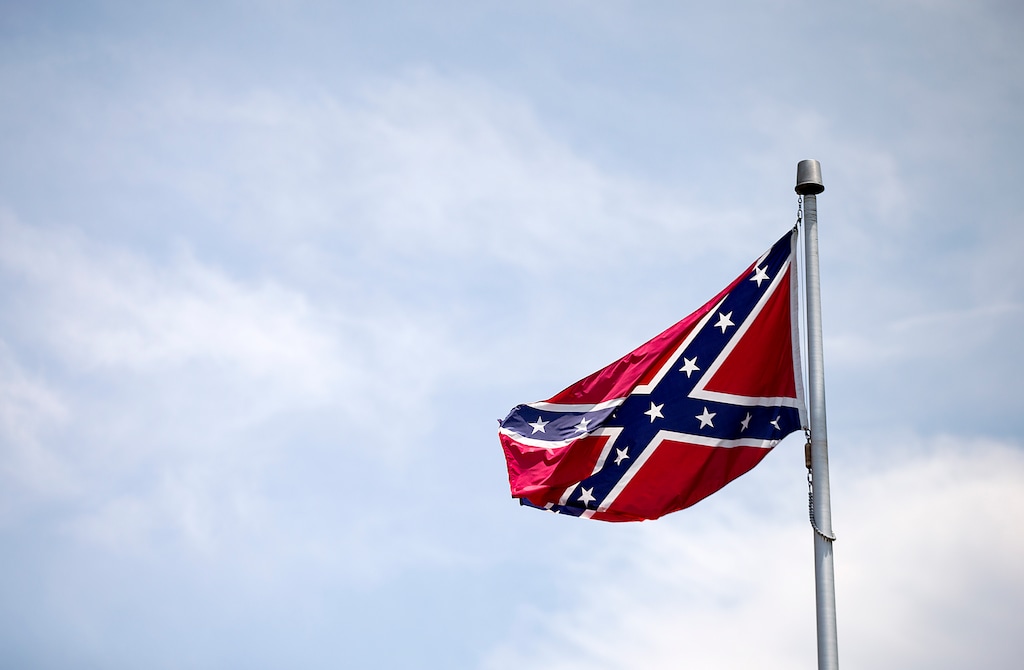 A Confederate flag flies at the base of Stone Mountain Tuesday, June 30, 2015, in Stone Mountain, Ga. At Georgia's iconic Stone Mountain, where the Confederacy is enshrined in a giant bas-relief sculpture, the Ku Klux Klan once held notorious cross-burnings and rebel battle flags still wave prominently, officials are considering what to do about those flags. The park, which now offers family-friendly fireworks and laser light shows, is readying its "Fantastic Fourth Celebration" Thursday through Sunday, and multiple Confederate flag varieties are still displayed at the mountain's base. (AP Photo/David Goldman) 