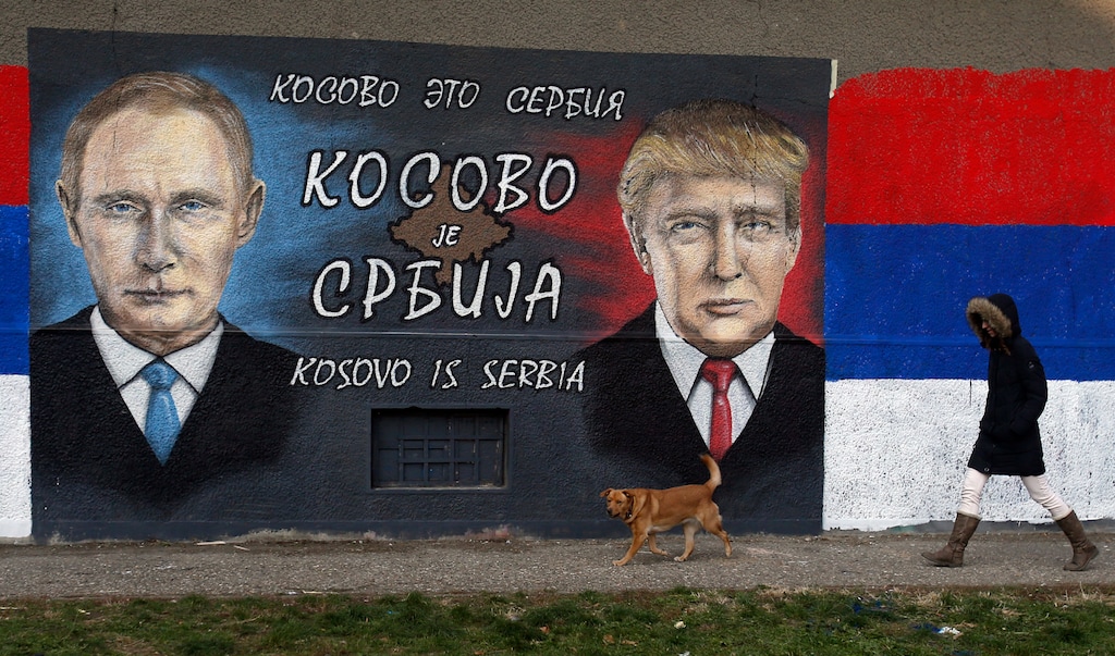 FILE - In this Tuesday, Dec. 6, 2016, file photo, a woman passes by graffiti depicting the Russian President Vladimir Putin, left, and US President Elect Donald Trump in a suburb of Belgrade, Serbia. The Cyrillic letters on graffiti read "Kosovo is Serbia", as Serbia doesn't recognise Kosovo's independence. U.S. President Donald Trump has urged Serbia and Kosovo to make a ''historic'' deal that would bring ''long-sought'' peace to the Balkan region. (AP Photo/Darko Vojinovic, File)