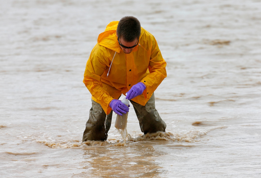 Hydrologic Technician Ryan Parker gathers water samples from the San Juan River, Tuesday, Aug. 11, 2015, in Montezuma Creek, Utah. A spill containing lead and arsenic from the abandoned Gold King Mine in Silverton, Colo., leaked into the Animas River, which flows into the San Juan River in southern Utah, on Aug. 5. The spill was caused by a mining and safety team working for the EPA.  (AP Photo/Matt York) 
