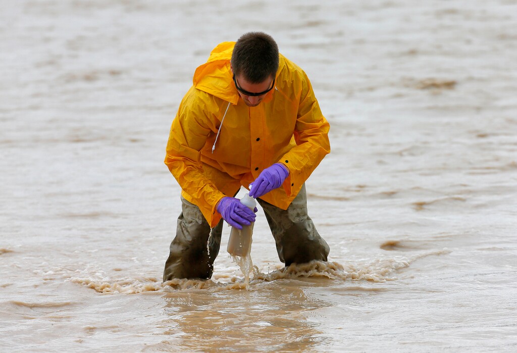 Hydrologic Technician Ryan Parker gathers water samples from the San Juan River, Tuesday, Aug. 11, 2015, in Montezuma Creek, Utah. A spill containing lead and arsenic from the abandoned Gold King Mine in Silverton, Colo., leaked into the Animas River, which flows into the San Juan River in southern Utah, on Aug. 5. The spill was caused by a mining and safety team working for the EPA. (AP Photo/Matt York)