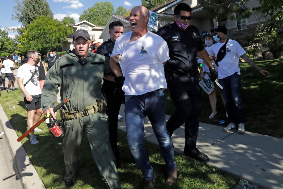 A protester is led away by Cottonwood Heights police officers during a march Sunday, Aug. 2, 2020, in Cottonwood Heights, Utah. The protest was a "March for Justice" focused largely around Zane James, who was fatally shot by police in Cottonwood Heights in 2018. (AP Photo/Rick Bowmer)