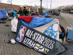 (Robin Pendergrast) A person experiencing homelessness uses a discarded All-Star Game banner as part of their shelter as Salt Lake City police patrol the area around 500 West in Salt Lake City, Thursday, March 2, 2023.
