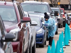 (Leah Hogsten | The Salt Lake Tribune) A steady line of vehicles filled with multiple people waiting to be tested for Covid19 are tended to by members of the Utah Department of Health at the Cannon Health Building, Dec. 27, 2021. 